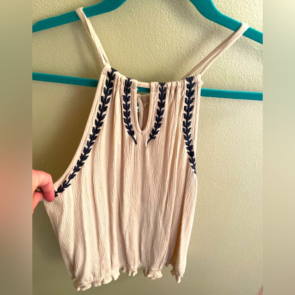 A tan halter top with a design around the arms and neck.